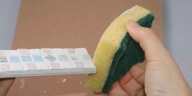 Mosaikkreuz mit dem Schwamm säubern