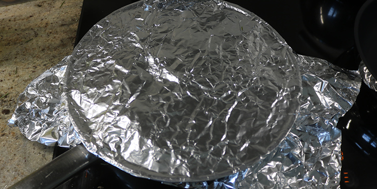 Paella mit Alufolie abdecken.