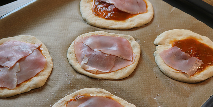 Pizza mit Schinken belegen.