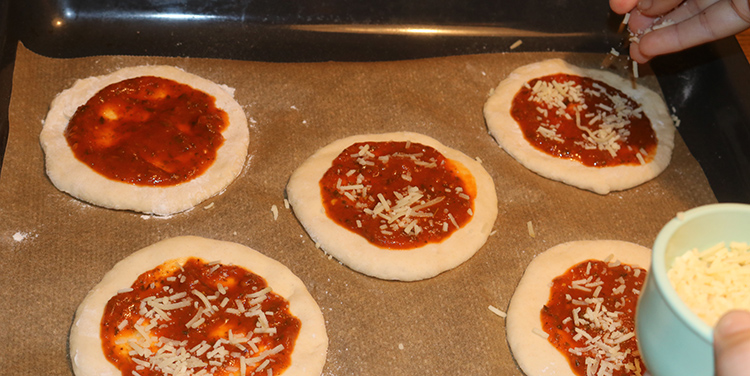 Pizzetten mit Tomatensauce und Käse belegen.